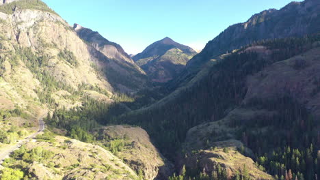 Luftdrohne-Senkt-Die-Bewegung-Der-Wunderschönen-Ouray-Colorado-Bergkette-Und-Autos,-Die-Auf-Der-Autobahn-550-Fahren,-Umgeben-Von-Dichten-Kiefernwäldern-Und-Stromleitungen-In-Den-Rocky-Mountains
