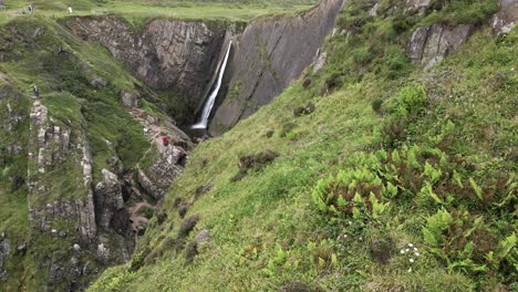Tilt-Up-Reveal,-Spekes-Mill-Mouth-Waterfall-in-Rolling-Green-Hills,-North-Devon