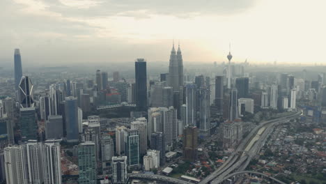 Aerial-shot-of-Kuala-Lumpur-skyline-and-Petronas-Twin-Towers,-grey-day