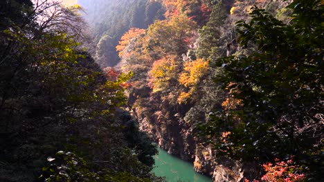 Wunderschönes-Herbstlaub-Gegen-Türkisfarbenes-Wasser-Im-Sonnenbeschienenen-Tal-In-Zeitlupe