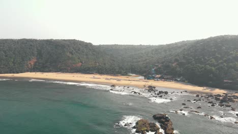 Serene-Arambol-beach-surrounded-by-lush-hills,-Goa,-India