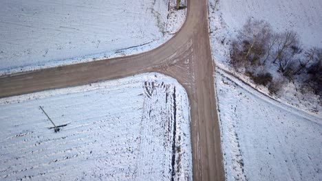 Aerial-flying-backwards-shot-of-countryside-road-during-snowy-season