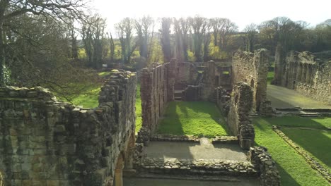 Basingwerk-abbey-landmark-medieval-abandoned-Welsh-ruins-Aerial-view-close-rising-shot-over-gardens