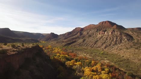 A-slow-aerial-descent-into-the-ribbon-of-colorful-fall-foliage-at-Sycamore-Canyon,-Northern-Arizona