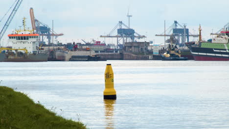 yellow-buoy-floating-on-river-near-shore-line