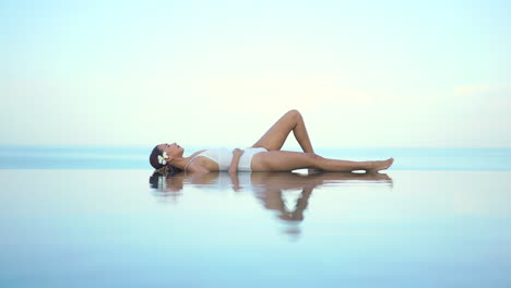 Attractive-Asian-Female-Laying-on-Infinity-Pool-Border-Between-Water-and-Endless-Horizon