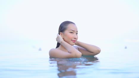 Young-Asian-woman-strokes-her-wet-hair-in-pool