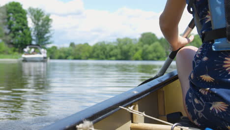 Young-woman-begins-paddling-a-canoe-down-a-river-on-a-sunny-summer-day