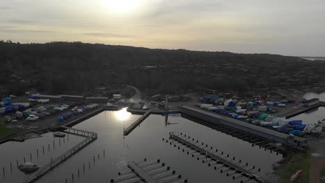Antenne-Des-Fischerdorfhafens-Mit-Mehreren-Booten-Und-Sonne,-Die-Sich-Auf-Dem-Wasser-Widerspiegeln