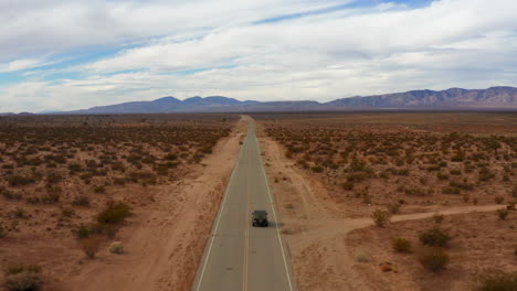 Aerial,-Flying-Behind-Jeep-Driving-on-Highway-in-Epic-Mojave-Desert-Landscape