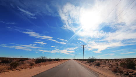 Driving-down-a-lonely,-empty-road-straight-through-the-Mojave-Desert---point-of-view-hyper-lapse