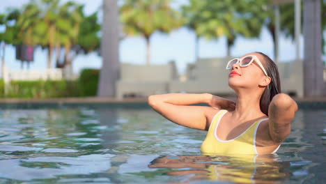 Mädchen-Mit-Sonnenbrille-Und-Gelbem-Badeanzug-Streichelt-Ihr-Nasses-Haar-Im-Pool