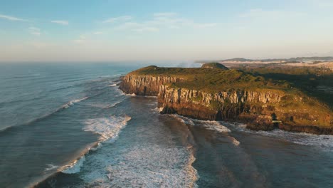 Tropical-beach-rocky-cliffs-on-atlantic-ocean-at-sunrise