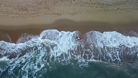 Aerial-Top-Down-View-Of-Tropical-Beach,-Waves-Crashing-Over-Adult-Male-Laying-Down
