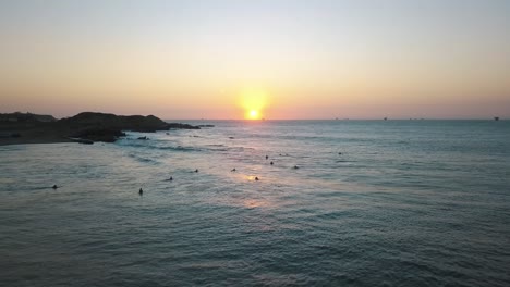 Luftaufnahme,-Sonnenuntergang-über-Dem-Pazifischen-Ozean-Und-Surfer-Mit-Board-Warten-Auf-Wellen-An-Der-Küste-Von-Peru