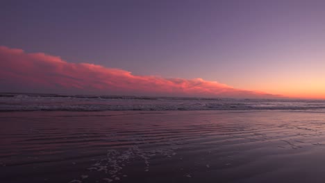 Waves-rolling-on-the-sand-under-a-purple-red-night-sky--wide