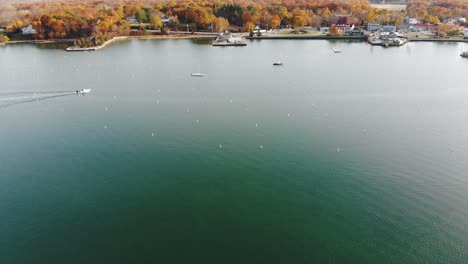 Flyby-drone-shot-of-a-motorboat-moving-from-left-to-right-on-a-harbor-in-Massachusetts-4K