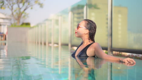 Well-enjoying-the-waters-of-an-urban-resort-rooftop-pool-pretty-woman-sunbaths