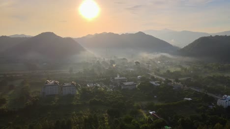 Aerial-4k-drone-footage-flying-over-a-small-rural-village-in-a-valley-between-two-mountain-ranges-in-Khao-Yai,-Thailand-during-sunset