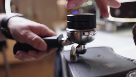 Barista's-Hand-Using-Coffee-Distributor-And-Tamper-To-Press-The-Freshly-Ground-Coffee-Bean-On-Portafilter