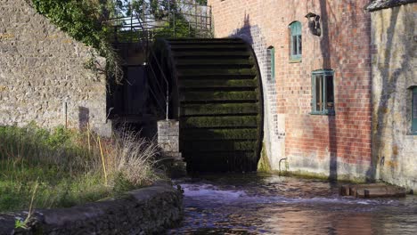 An-old-wooden-undershot-waterwheel-on-the-side-of-a-historic-water-mill-in-Lower-Slaughter-in-the-Cotswolds