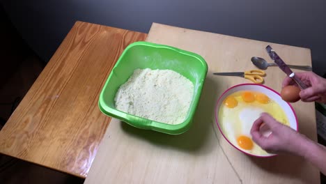 Person-Cracking-Eggs-In-A-Bowl-On-The-Kitchen-Table
