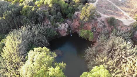 Pego-do-Inferno-hidden-lake-and-waterfall-in-Tavira,-Algarve,-Portugal---Survey-Orbit-Aerial-shot