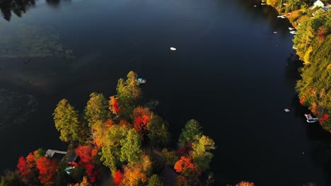 Aerial-View-of-Boat-Sailing-on-Picturesque-Lake-With-Colorful-Autumn-Forest-and-House-on-Lakefront,-Drone-Shot