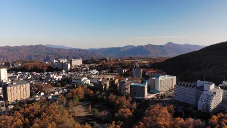 Rotating-drone-view-over-Mountain-town-in-Japan-on-bright-blue-day-with-autumn-colors