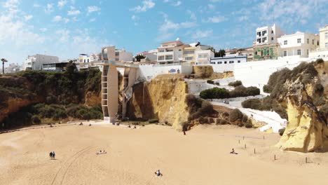Aerial-4k-drone-footage-flying-over-a-sandy-beach-and-up-the-rocky-cliffs-towards-a-large-condo-of-the-coastal-European-resort-town-of-Albufeira,-Portugal