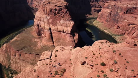 Tourists-Stand-At-The-Lookout-Viewpoint-Of-Horseshoe-Bend-In-Arizona,-Aerial-Flyover