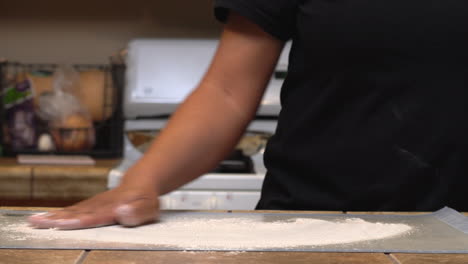 Sprinkling-flour-on-the-rolling-board-before-the-homemade-dough