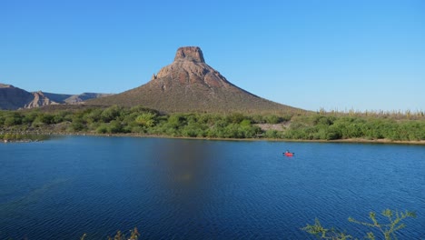 Establishing-Shot,-red-boat-floating-on-the-river-of-La-Purisima,-Baja-California-sur,-Mexico,-Scenic-view-of-the-El-Pilón-mountain-in-the-background