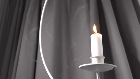Beautiful-white-candle-surrounded-by-smoke,-low-angle-slow-motion