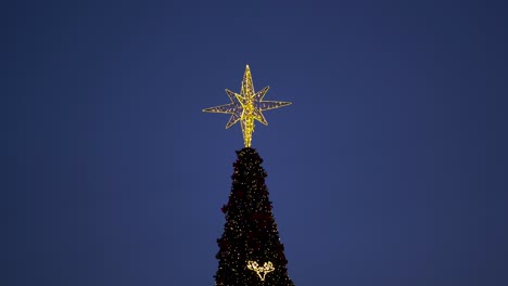 Estrella-Amarilla-Brillante-En-La-Parte-Superior-Del-árbol-De-Navidad-Con-Adornos-Brillantes-En-El-Fondo-Del-Cielo-Nocturno