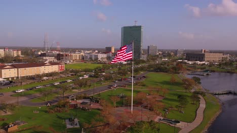 Bandera-Estadounidense-Y-Parque-Conmemorativo-De-Veteranos-En-El-Lago-Charles-Con-El-Edificio-Capital-One-Dañado-En-Louisiana-Después-Del-Huracán-Laura