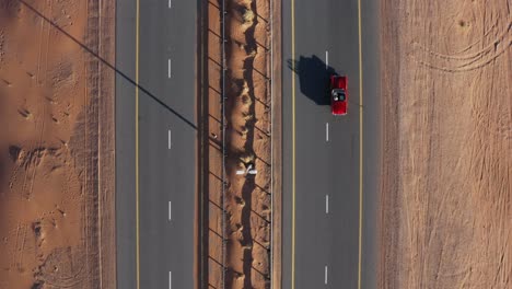 Aerial-View-Of-Red-Classic-Car-Driving-On-Remote-Desert-Road-At-Daytime---wide-top-down-shot