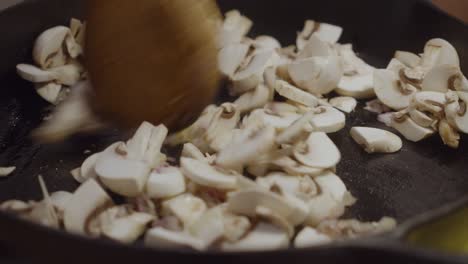 Stirring-and-mixing-up-white-mushrooms-with-onion-slices-inside-hot-frying-pan