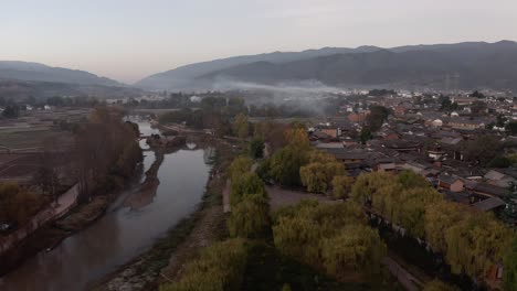 Shaxi-historic-Chinese-town-in-Yunnan-province,-China,-misty-sunrise-aerial-view