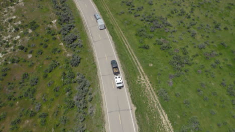 Scenic-Aerial-chasing-two-vehicles-with-recreational-trailers-driving-in-the-midwestern-US,-Colorado-roads