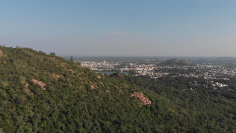 Langsame-Vorwärtsaufnahme-Aus-Der-Luft-Eines-überwucherten-Berges-Mit-Der-Schönen-Stadt-Tiruvannamalai-Im-Hintergrund