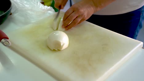 Mujer-Cortando-Cebolla-Blanca-Usando-Un-Cuchillo-Pequeño-En-Una-Tabla-De-Cortar-En-La-Cocina