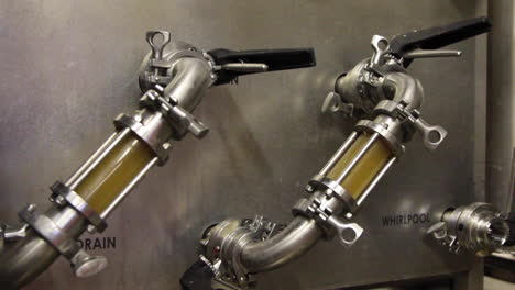 Fresh-beer-flowing-through-metal-pipeline-of-beer-tank-in-factory
