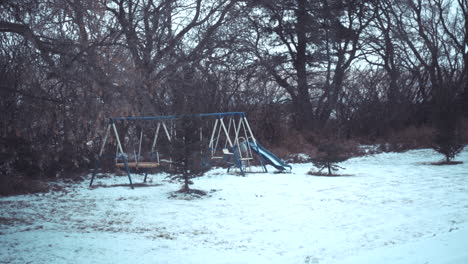 Snowfall-on-a-children's-play-set-in-the-winter-time-at-a-farm-in-slow-motion