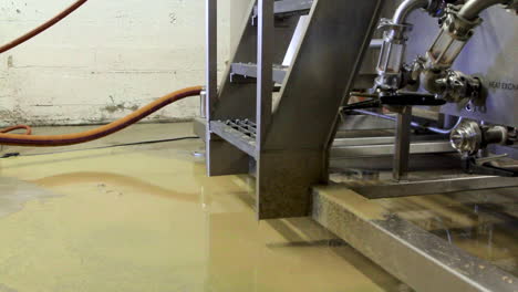 Beer-residues-liquid-leaking-out-of-tap-on-the-ground-in-industrial-beer-factory