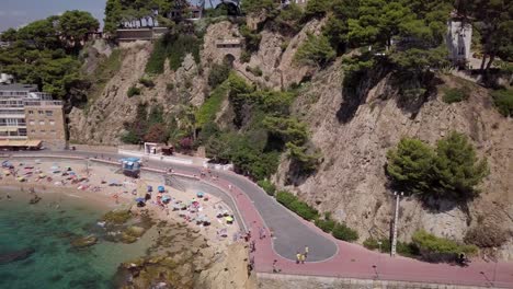 Zoom-out-of-a-large-rock-with-houses-on-top-in-Spain,-Lloret-de-Mar