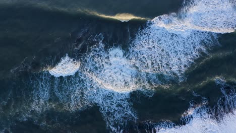 Waves-Breaking-On-The-Black-Sandy-Shore-Of-A-Quiet-Secluded-South-Coast-Beach---aerial-drone