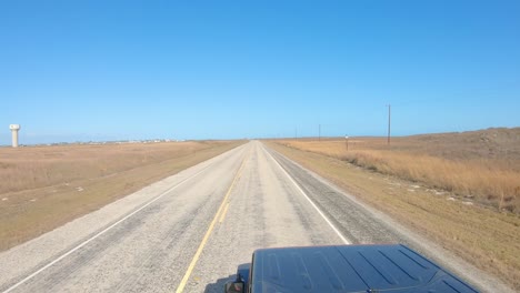 View-of-vehicle-roof-top-while-driving-on-a-paved-road-thru-grasslands-towards-water-tower-on-North-Padre-barrier-island-along-the-gulf-shore-of-Texas-in-mid-afternoon