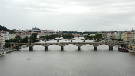 Aerial-push-out-of-bridge-over-Vltava-River-and-Prague-cityscape
