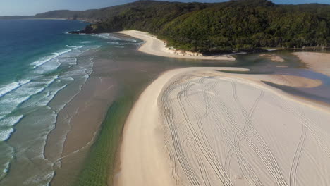 Tilting-up-drone-shot-of-Sandbar-Beach,-inlet-into-Smith-Lake-in-New-South-Wales-Australia